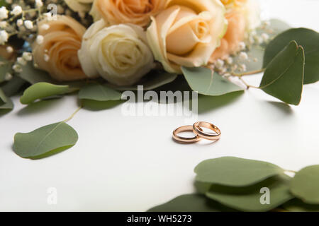 Trauringe mit Rosen auf weißem Hintergrund Stockfoto