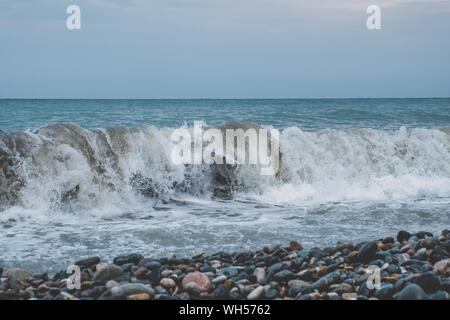 Stürmische Wellen auf dem Meer an einem trüben Tag. Große Wellen von einem stürmischen Meer Absturz auf einem Kieselstrand. Stockfoto