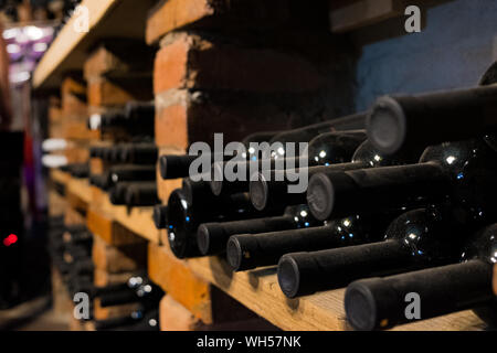 Flaschen Wein im Keller, selektive konzentrieren. Jahrgang Wein mit Korkgeschmack in einem schwach beleuchteten Bar oder Keller, Nahaufnahme Stockfoto