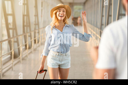 Mann treffen Frau am Flughafen Terminal, gastfreundliches Haus zurück Stockfoto