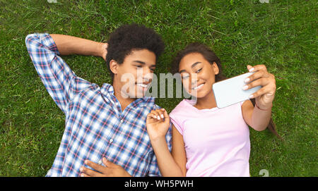 Teenage Paar selfie machen bei der Verlegung auf Gras Stockfoto