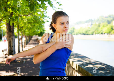 Cute teen Mädchen in Blau t-shirt zu tun Stretching Übungen im Freien Stockfoto