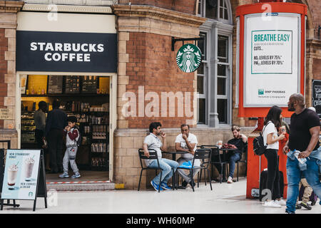 London, Großbritannien - 18 Juli, 2019: die Menschen an den Tischen von Starbucks im Bahnhof Marylebone, London. Starbucks ist eine berühmte amerikanische Kaffeehaus Kette. Stockfoto