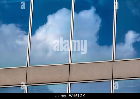 Wolken reflektieren: das Bestehen der flauschigen weissen Wolken am Fenster eines modernen Gebäude in der Paddington Basin wider.