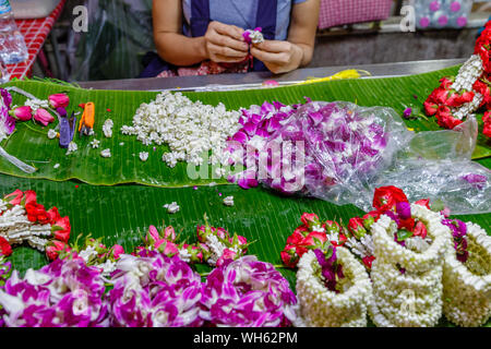 Frau, die Phuang malai, traditionelle Thai Flower Garland Angebote mit Jasmin und Orchideen bei Pak Khlong Talat, Bangkok Blumenmarkt. Thailand. Stockfoto