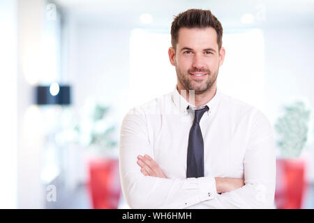 Portraitfotos von lächelnden Geschäftsmann mit Hemd und Krawatte beim Stehen im Büro und lächelnd. Stockfoto