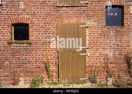 An der vorderen Wand eines alten Bauernhofes Gebäude aus roten Ziegelsteinen Stockfoto