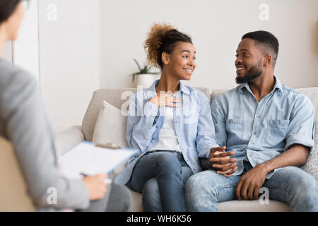 Fröhliche Afro Paar teilen Nachrichten mit ehelichen Therapeuten nach der Synchronisierung Stockfoto