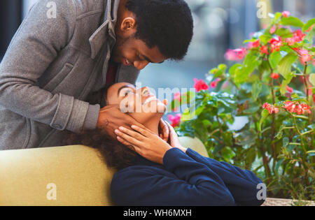 Afro Kerl in Liebe seine Freundin Gesicht berühren von hinten Stockfoto