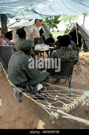 Lt Colonel Andrew Parker Bowles, Zentrum mit blauer Ordner, im Camp Alpha, Rhodesia-Zimbabwe 1980. Er ist gesehen, die Überwachung der Patriotischen Front Truppen aus der Buchse in der Britischen Armee laufen Holding camps in der Zambezi Tal als Teil der Lancaster House Friedensprozess nach den Rhodesian Bürgerkrieg beendet. Er war Leitender Militärischer Verbindungsoffizier zu Lord Soames, als er Gouverneur von Rhodesien während der Übergang zum Mehrheitsprinzip Zustand von Simbabwe 1979 - 1980. Er war Mitarbeiter Qualifizierte (SQ), und wurde ein Oberstleutnant vom 30. Juni 1980. AK47 AK47 Er die Queen's Commendation fo ausgezeichnet wurde Stockfoto