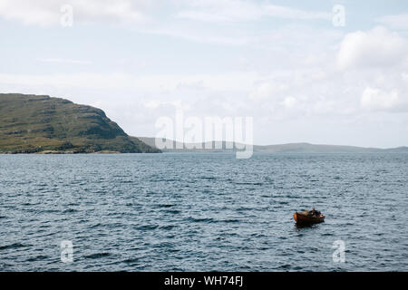 Creel Fischer in seinem kleinen hölzernen Hummerboot in der Nähe von ullapool wirft seine Fallen. Stockfoto