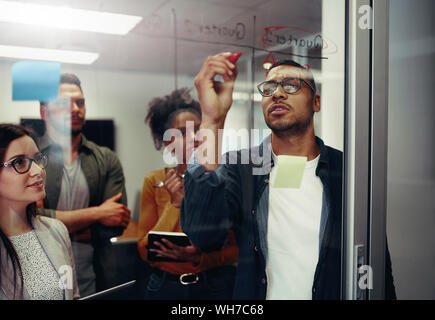 Kollegen suchen Bei Geschäftsmann schreiben auf Glas Wand Unternehmer Stockfoto