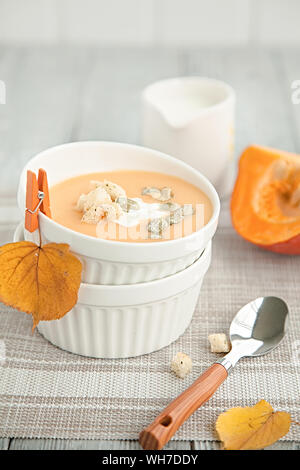 Kürbis creme Suppe in eine weiße Platte und im Herbst gelb Blatt. Herbst Zusammensetzung Stockfoto