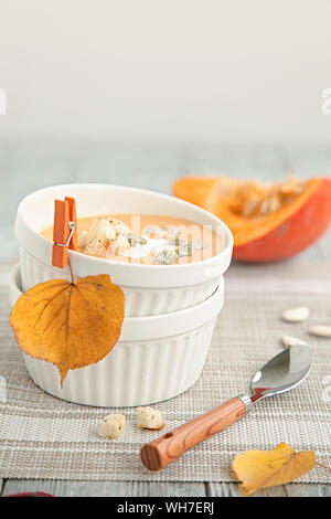 Kürbis creme Suppe in eine weiße Platte und im Herbst gelb Blatt. Herbst Zusammensetzung Stockfoto