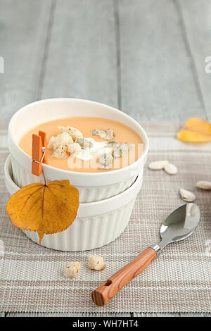 Kürbis creme Suppe in eine weiße Platte und im Herbst gelb Blatt. Herbst Zusammensetzung Stockfoto