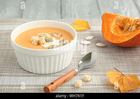 Kürbis creme Suppe in eine weiße Platte und im Herbst gelb Blatt. Herbst Zusammensetzung Stockfoto