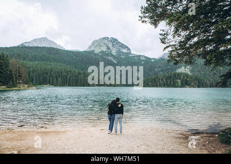 Ein paar bewundert die wunderschöne natürliche Landschaft - Schwarzer See in Montenegro. Die Zeit zusammen oder Urlaub oder Reisen Stockfoto