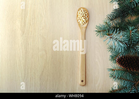 Cedar Pinienkerne in Löffel aus Holz mit Kegeln, Zeder brunch am Holz- Hintergrund. Ansicht von oben witn Kopie Raum Stockfoto