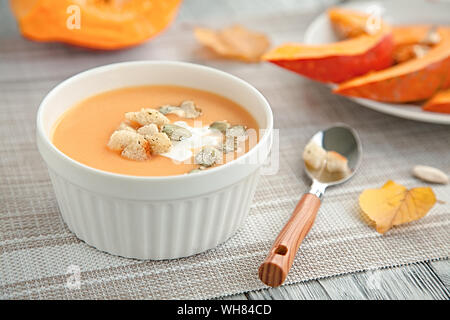 Kürbis creme Suppe in eine weiße Platte und im Herbst gelb Blatt. Herbst Zusammensetzung Stockfoto