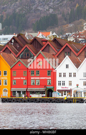 Bergen, Norwegen - 17. November 2017: Norwegische Stadt mit traditionellen roten Holzhäusern entlang der Küste, Bergen Bryggen. Gewöhnliche Menschen zu Fuß auf Th Stockfoto