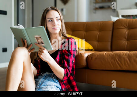 Junge Frau mit einem Fotoalbum zu Hause Stockfoto