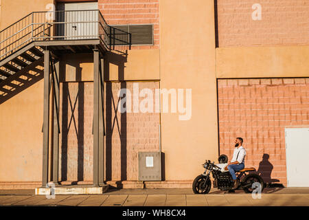 Laughing Man sitzt auf seinem Motorrad am Abend Stockfoto