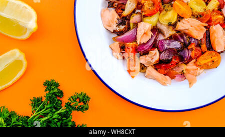 Gesunde, frische Lachsfilet mit gebratenem Gemüse, wie Tomaten, roten Zwiebeln und Knoblauch Stockfoto