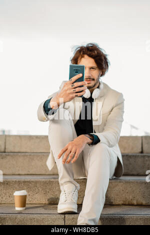 Mann mit dem tätowierten Finger unter selfie mit Smartphone Stockfoto