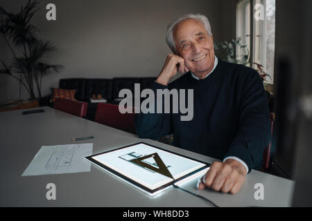 Lächelnd älterer Mann mit Tablet mit architektonischen Plan Stockfoto