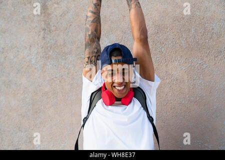 Portrait von tätowierten jungen Mann mit erhobenen Armen Stockfoto