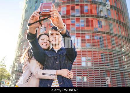 Portrait von Ehepaar miteinander reden selfie mit Instant Kamera, Barcelona, Spanien Stockfoto