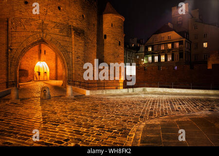 Straße mit Kopfsteinpflaster und Barbican Gate in die Altstadt bei Nacht, Warschau, Polen Stockfoto