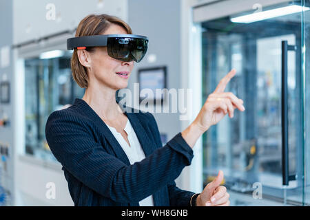 Geschäftsfrau tragen AR-Gläser in ein modernes Werk Stockfoto