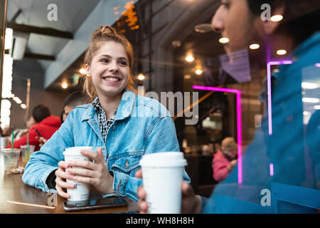 Portrait von lächelnden jungen Frau in einem Café an junge Menschen auf der Suche Stockfoto
