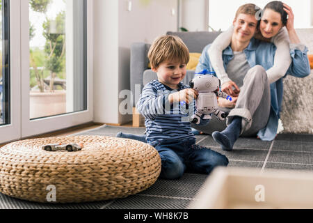 Eltern beobachten, Sohn, spielen mit Spielzeug Roboter Stockfoto