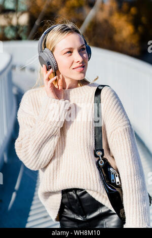 Portrait von Inhalt junge Frau hört Musik mit Kopfhörer im Freien Stockfoto