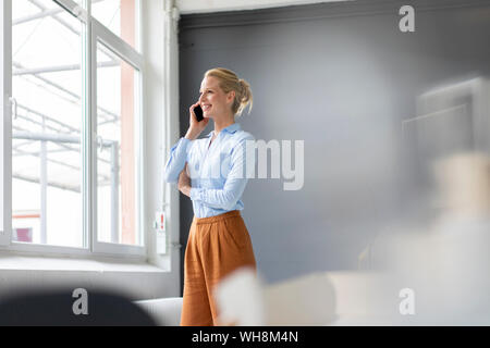 Lächelnden jungen Geschäftsfrau Gespräch am Handy im Büro Stockfoto