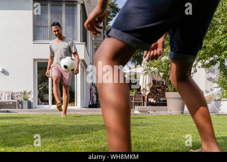 Vater und Sohn im Garten Fußball spielen Stockfoto