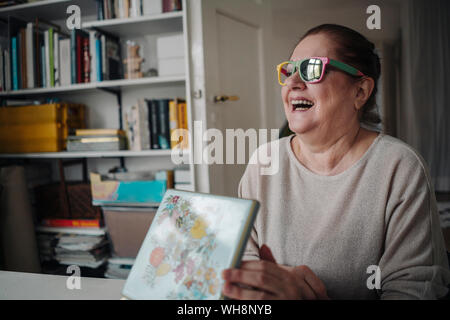 Gerne ältere Frau mit Sonnenbrille zu Hause gebrochen Stockfoto