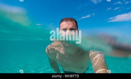 Man schwimmt auf der Oberfläche des Wassers, sowohl unter als auch über dem Wasser gesehen Stockfoto