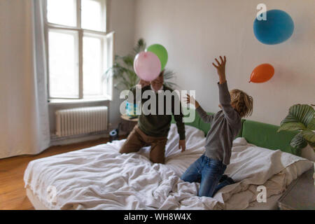 Gerne Großvater und Enkel spielen mit Ballons auf Bett zu Hause Stockfoto