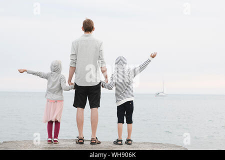 Rückansicht der Mann, der vor dem Meer mit kleinen Tochter und Sohn im Abstand suchen Stockfoto