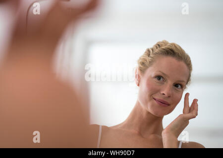 Porträt der schönen blonden Frau Anwendung Augencreme Stockfoto