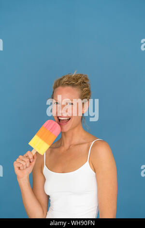 Portrait von blonde Frau mit großen Popsicle, blauer Hintergrund Stockfoto