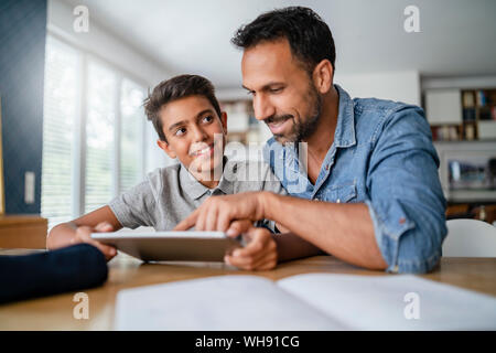 Vater und mit Tablet und Hausaufgaben Sohn Stockfoto