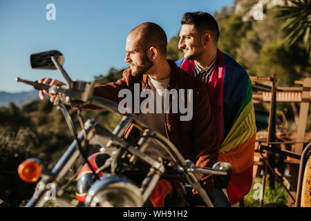 Ein schwules Paar mit Gay Pride Flagge auf einem Motorrad Stockfoto