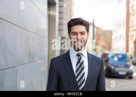 Porträt der Bärtige junge Unternehmer trägt blaue Anzug und Krawatte in der Stadt Stockfoto