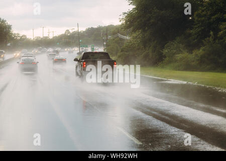 Der Verkehr auf der Autobahn während eines Sturms. Heavy Rain auf einer Straße ein Auto bei hoher Geschwindigkeit bewegen durch eine Pfütze auf einem überfluteten Straße Stockfoto