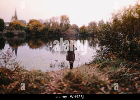 Zurück Blick auf die Frau, die an Wasser im Herbst Stockfoto