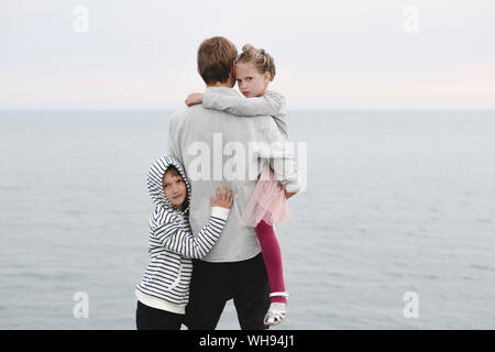 Rückansicht der Mann, der vor dem Meer mit kleinen Tochter und Sohn Stockfoto